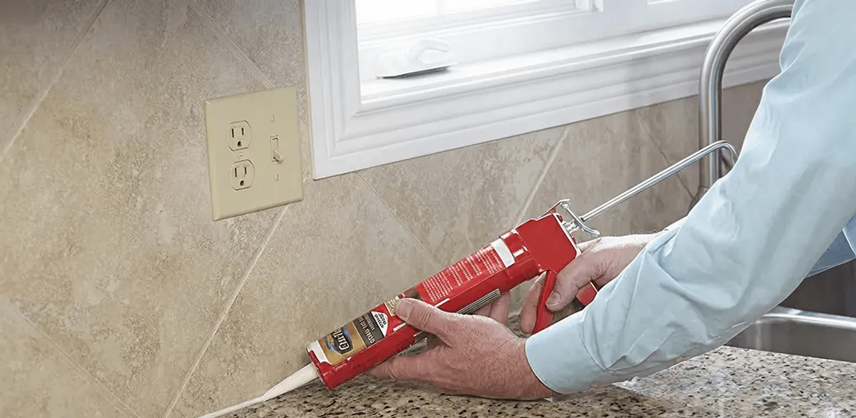 Handyman applying caulk along a kitchen backsplash and countertop seam in Madison, WI