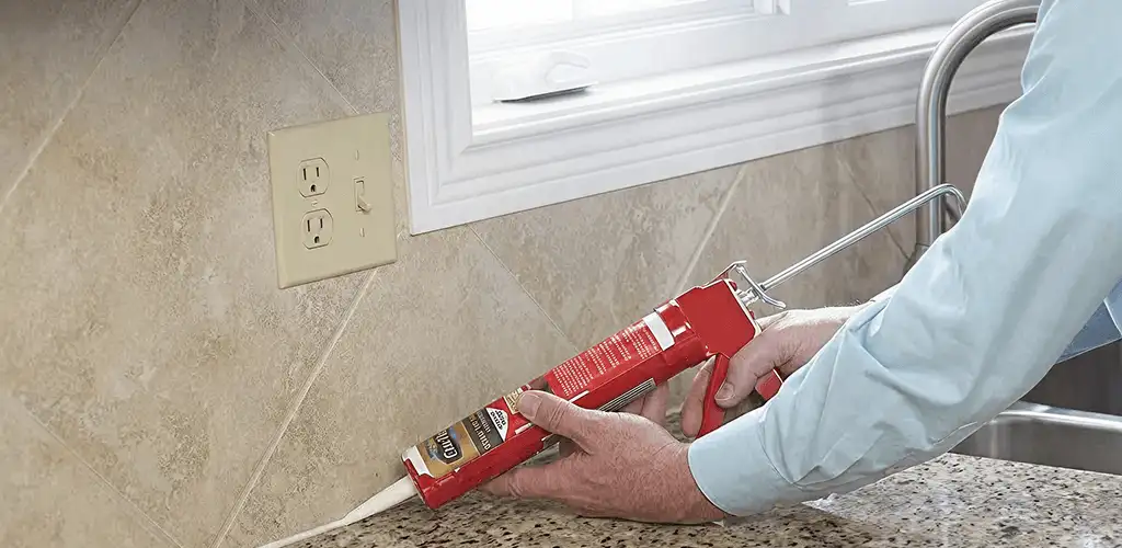 Handyman applying caulk along a kitchen backsplash and countertop seam in Madison, WI