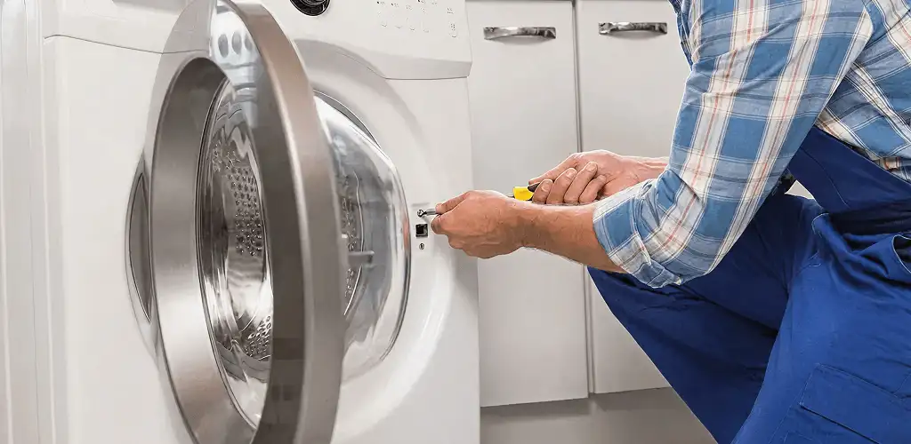 Handyman repairing a clothes dryer and checking electrical connections in Madison, WI
