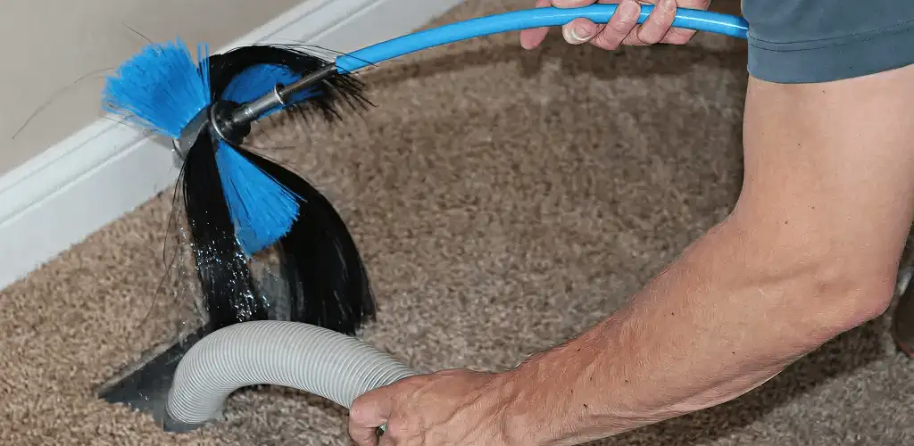 Dryer vent cleaning technician brushing lint from a vent line in Madison, WI