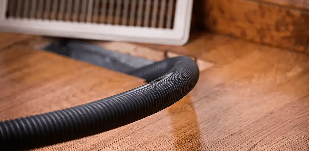 Air duct cleaning hose inserted into a floor vent for ductwork cleaning in Madison, WI