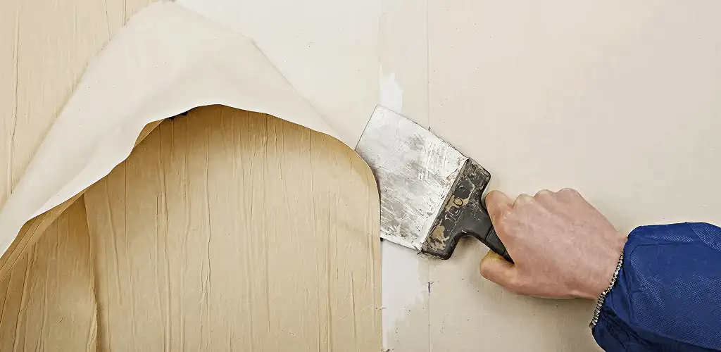 Handyman removing wallpaper with a scraper for wall preparation in Madison, WI