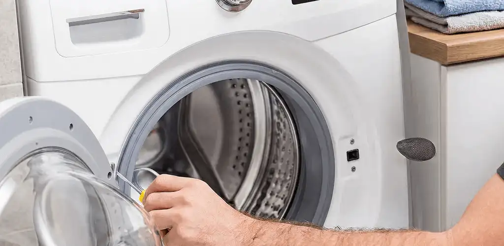 Handyman repairing a front-load washing machine and inspecting the drum in Madison, WI