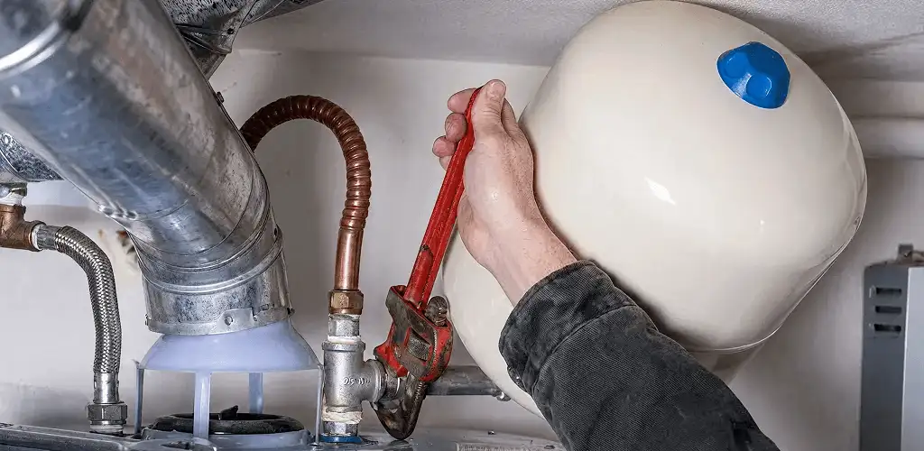 Water heater repair technician tightening plumbing connections near a tank unit in Madison, WI