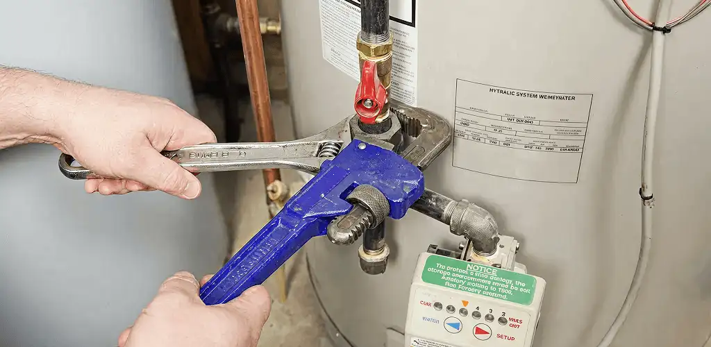Water heater repair technician tightening the shutoff valve and supply line in Madison, WI